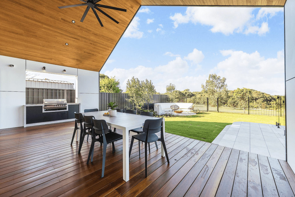 exterior backyard view of luxury home looking over wooden decking to the grass and bush
